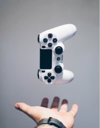 A modern white game controller which is being thrown upside by a hand